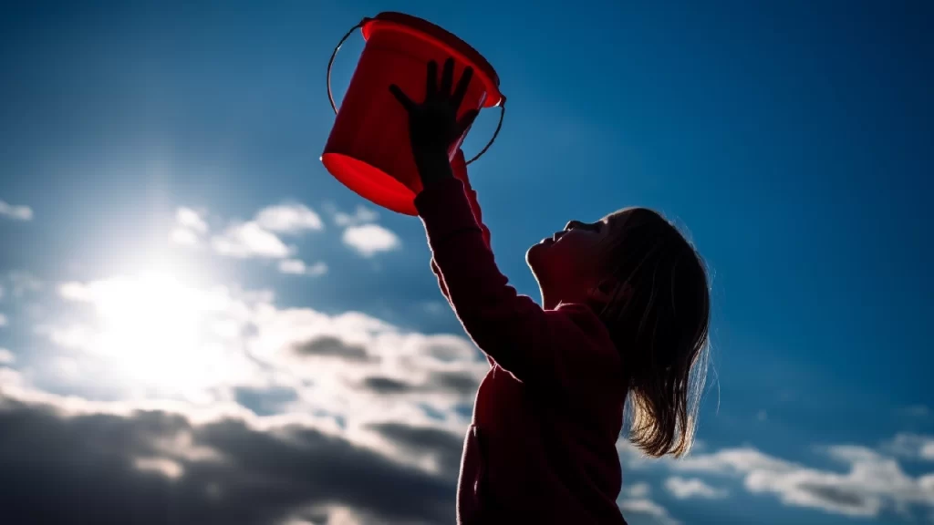 Little girl with red bucket catching sunshine